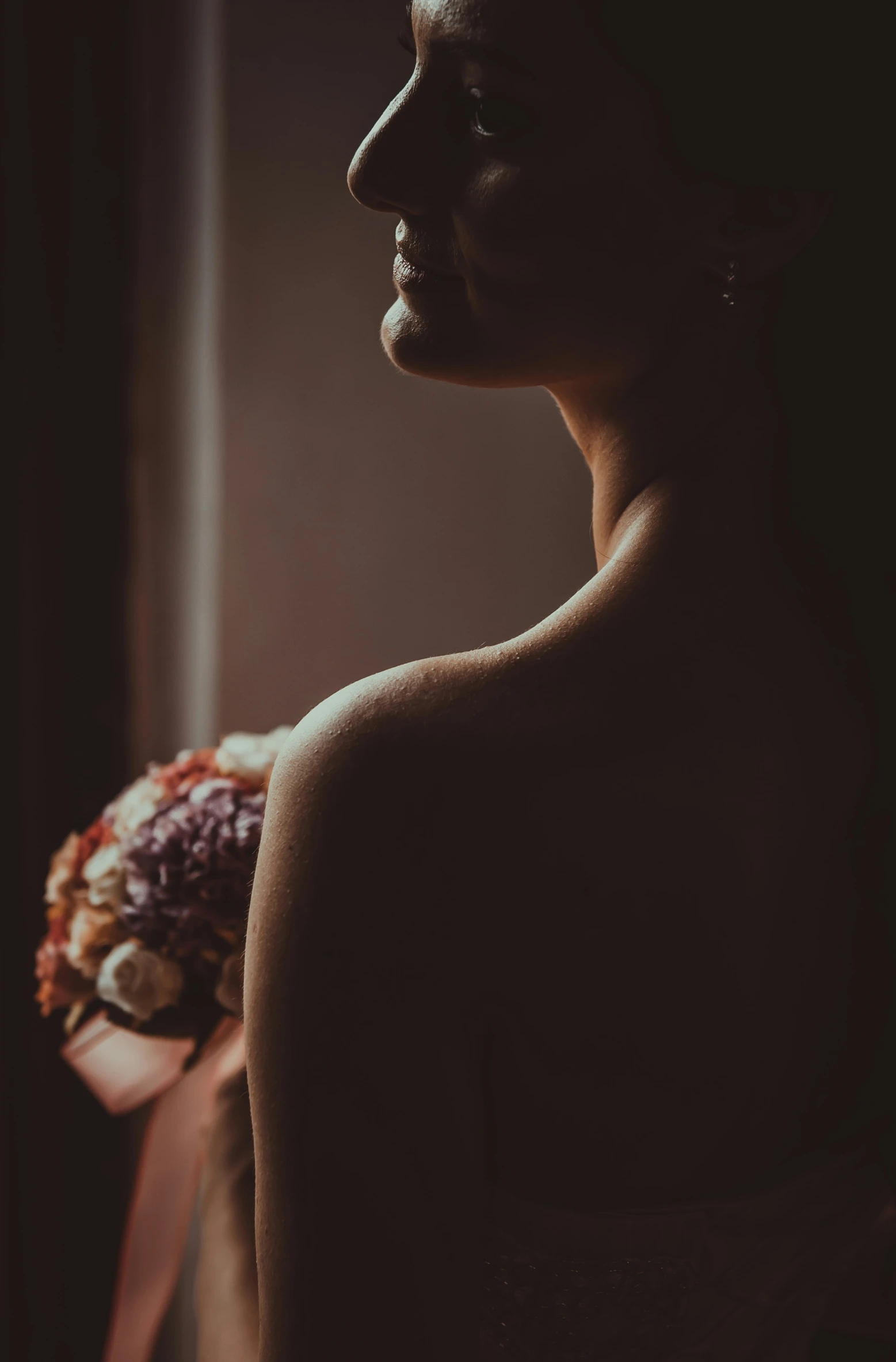 a bride holding a bouquet in a dimly lit room