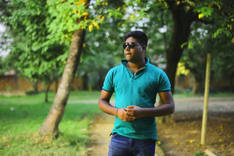 the young man in glasses is smiling with trees around