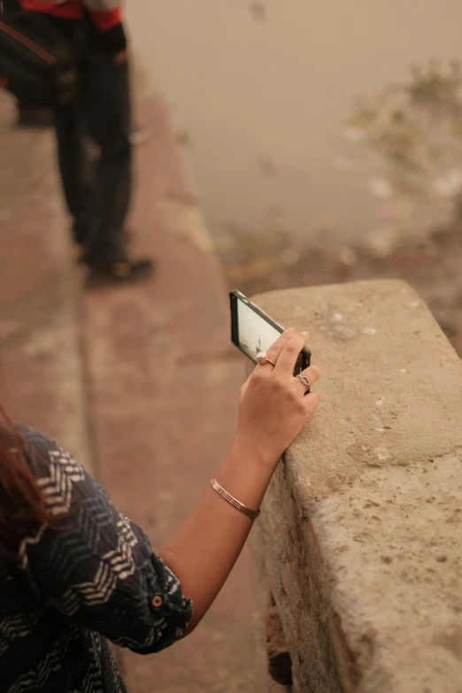 the woman is looking at her cell phone while standing near another man