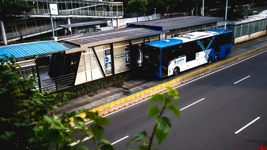 a blue and white bus driving by a building