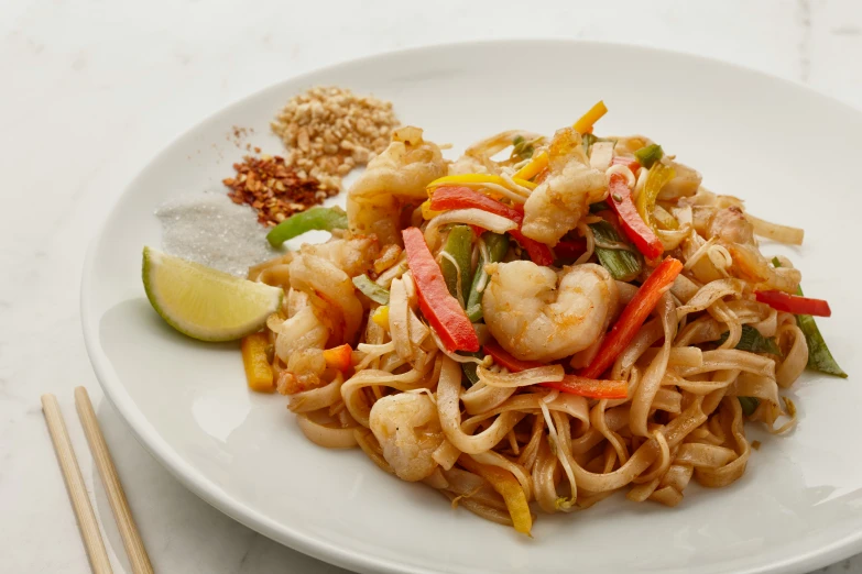 plate of noodles and shrimp with chili garnishes