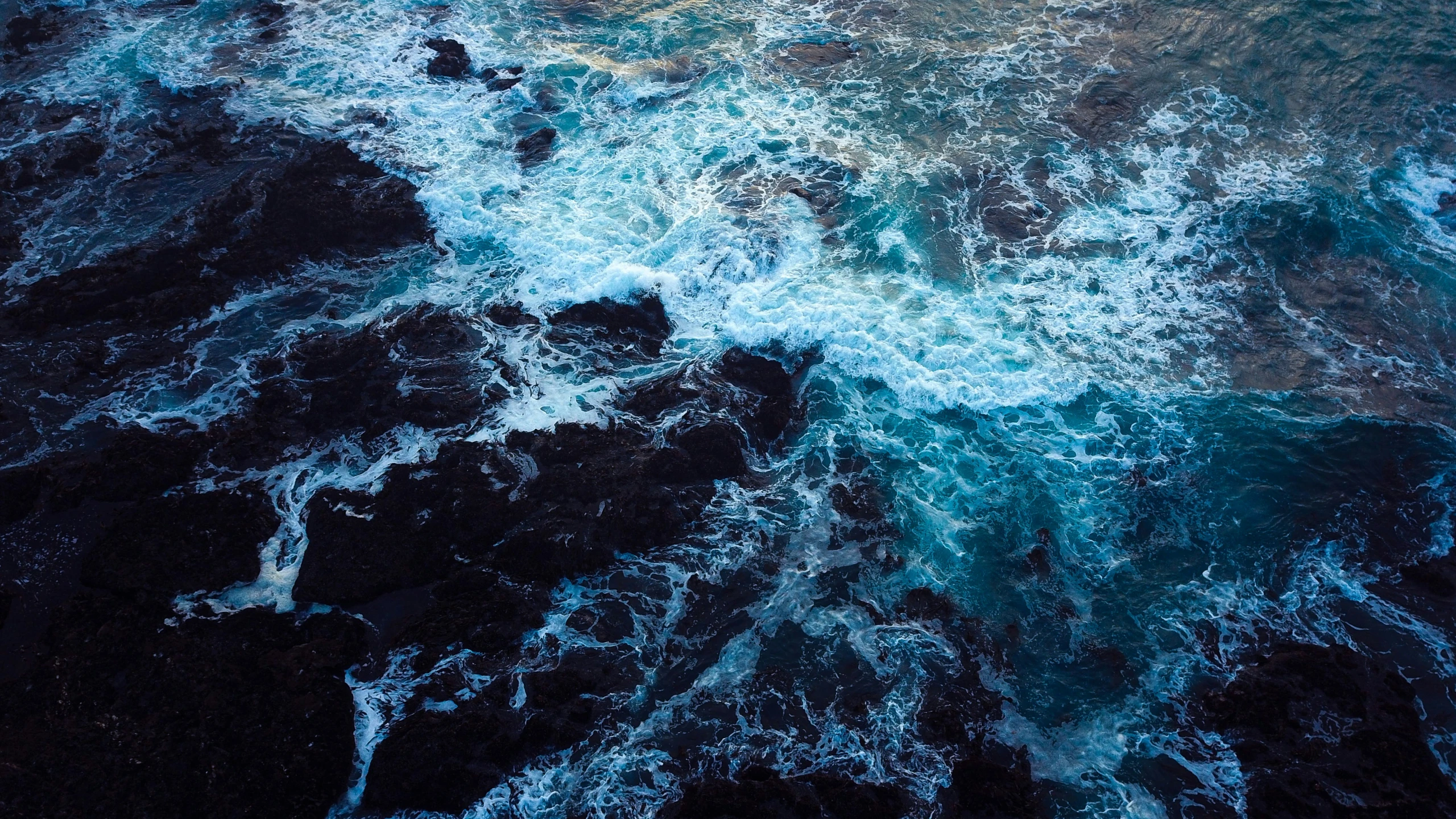 an aerial view of some water with rocks and a boat