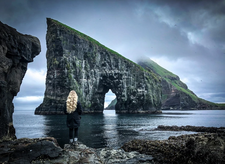 the woman is standing on the edge of a rock outcropping