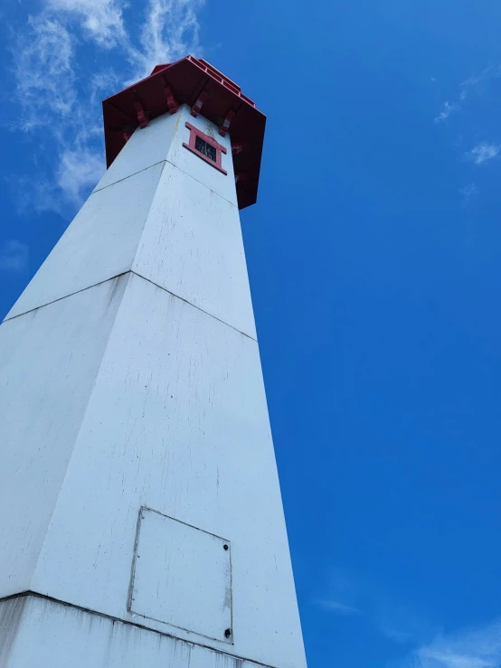 a tower with a red top sitting under a cloudy blue sky