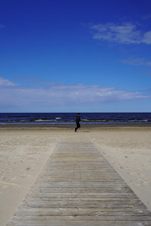 a person sitting on top of a wooden bridge on top of a sandy beach