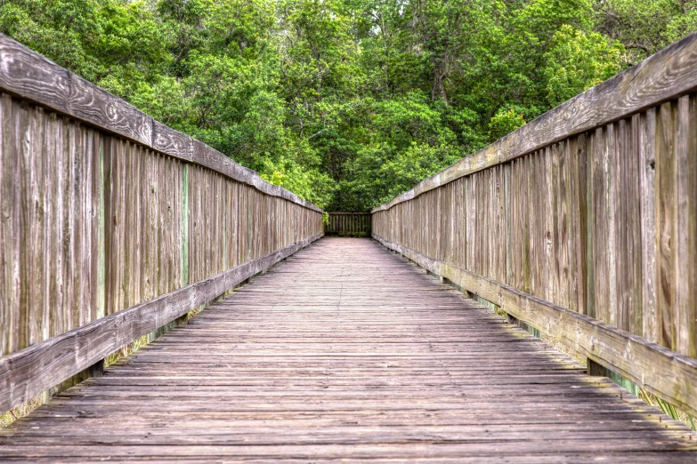 a wooden bridge with an end that has a small walkway in the middle