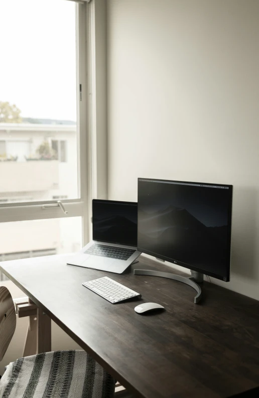 a laptop, a keyboard and a monitor are sitting on a desk