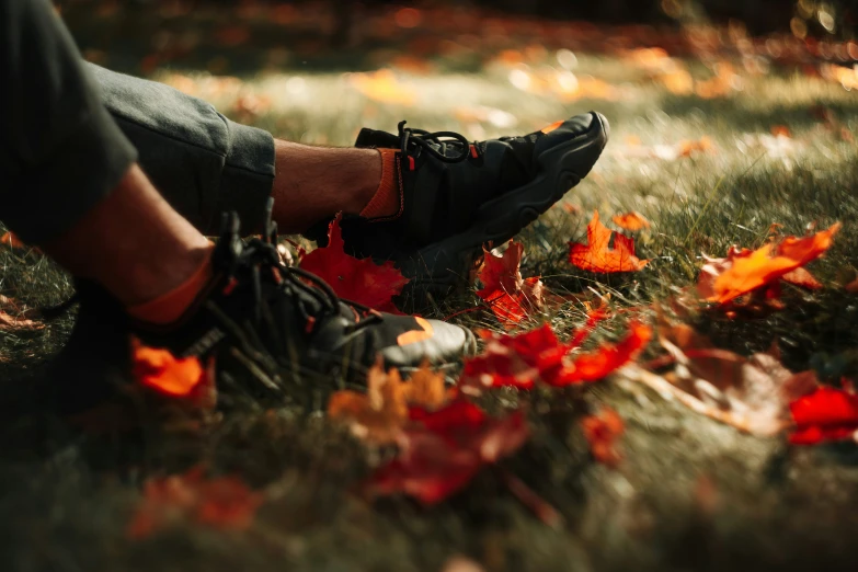 a person is standing in some leaves near sneakers