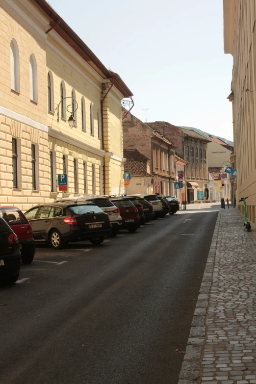 a street lined with rows of cars next to buildings