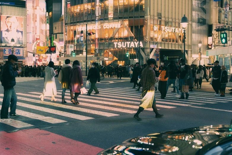 a cross walk with people crossing the street in front of a building at night