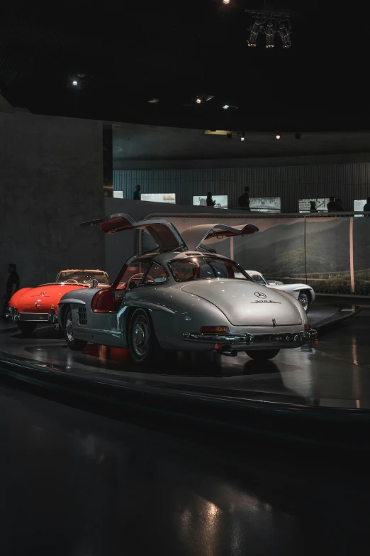 two large vehicles on a dark floor in an automotive museum