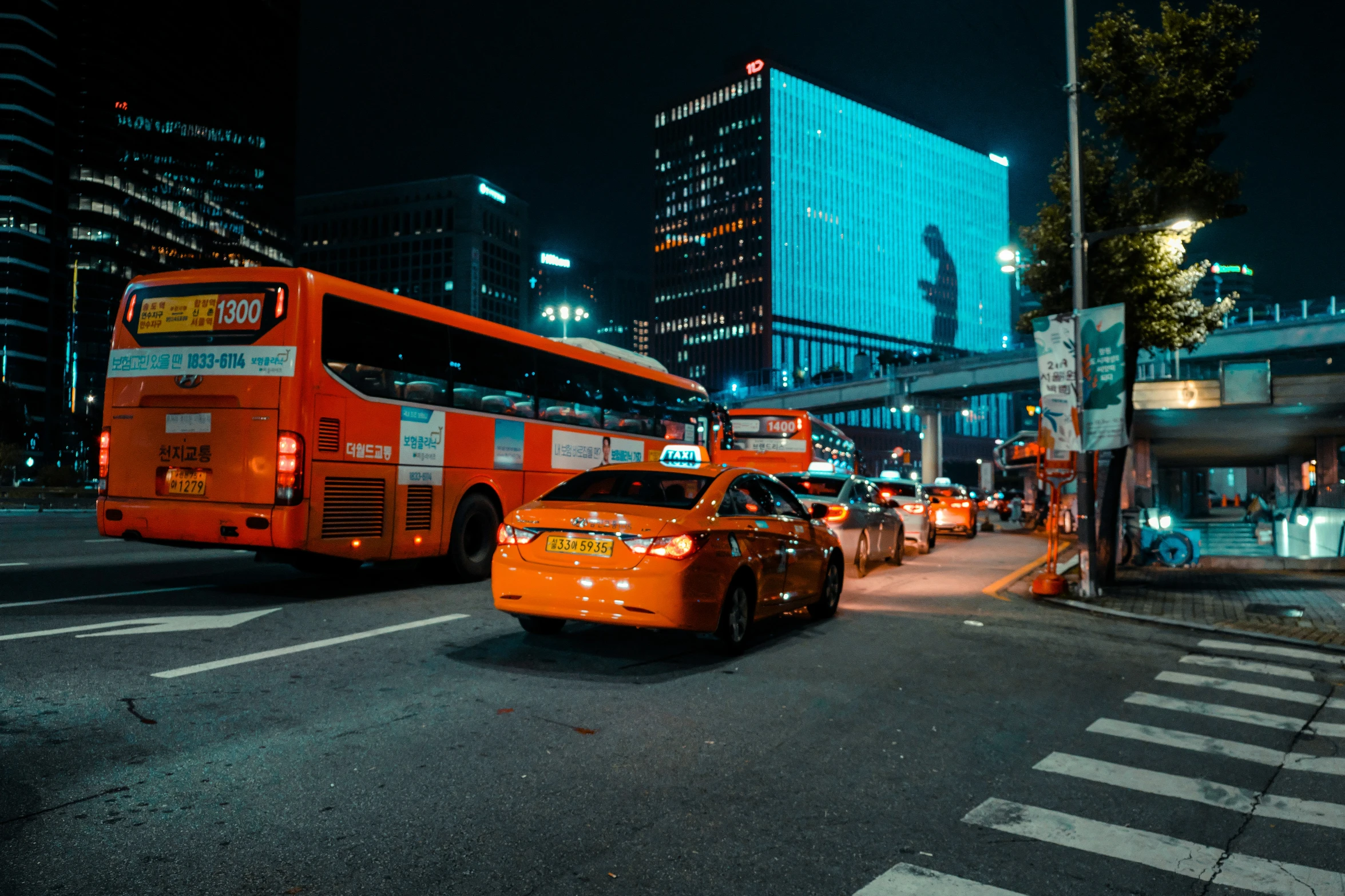 two orange vehicles are stopped at the curb