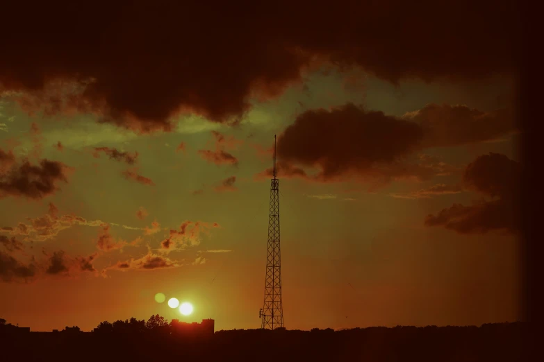 the sun setting in a field with dark clouds