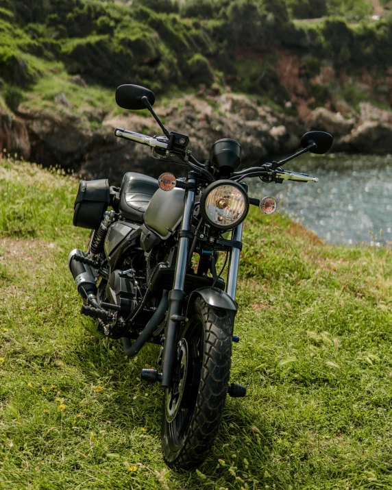 a motorcycle is parked in the grass near water