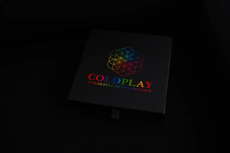 the front of a black book with multicolored letters that read coldplay