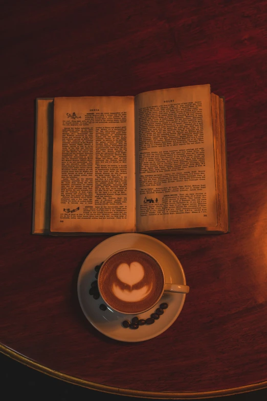 an open book, a heart drawn in a heart on it and a cappuccino cup on top