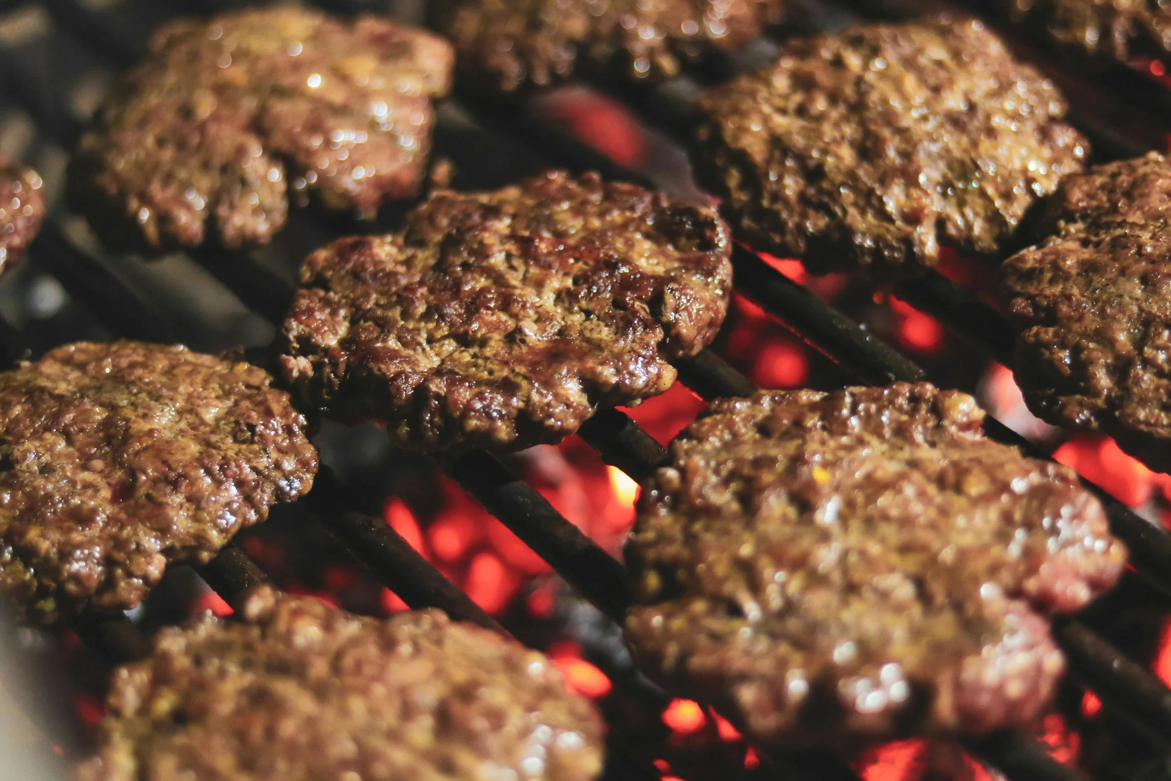 a bunch of burgers cooking on an open grill