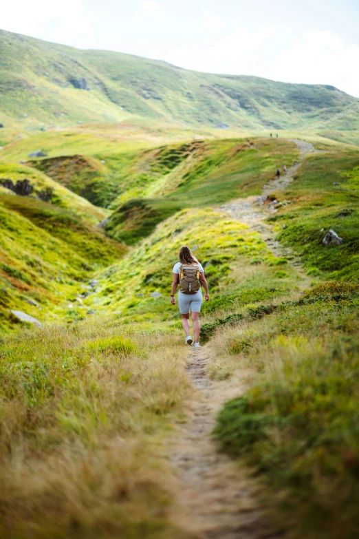 the woman walks down a path with backpack