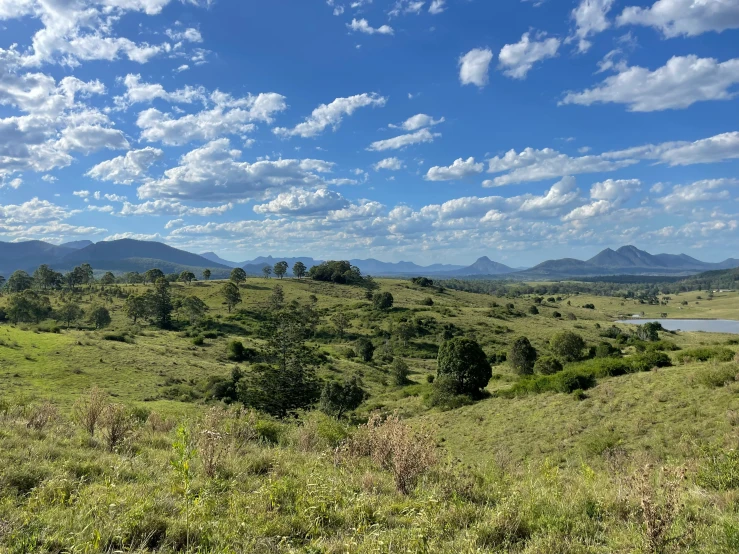 lush green hills and trees with some clouds in the sky