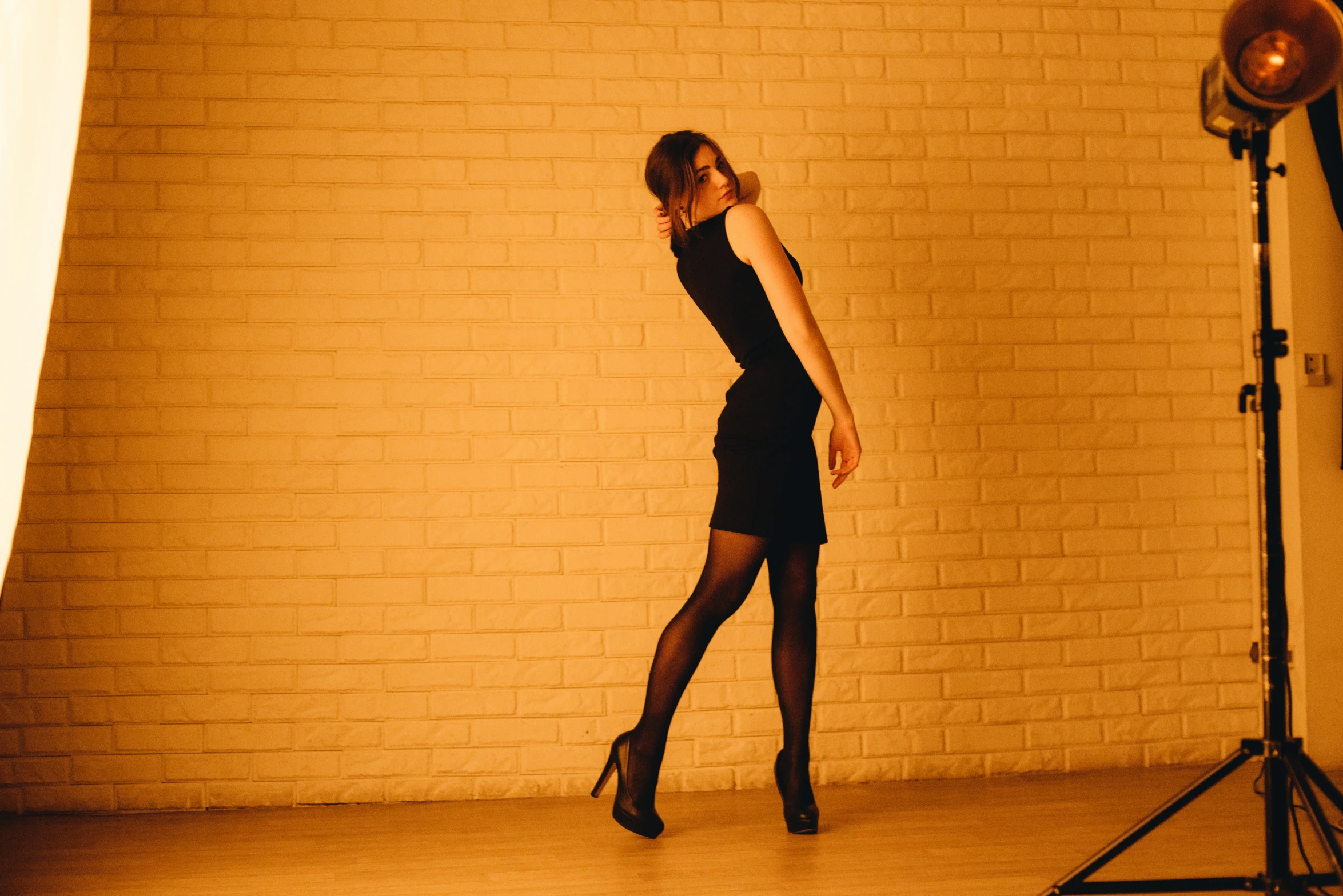 a woman in a black dress standing next to a brick wall