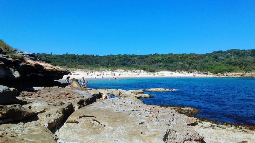 the view from the beach of a body of water near trees