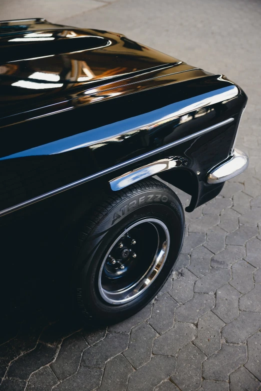 a car's hood in chrome and parked on a cobblestone driveway