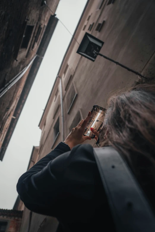 a person holding up a cell phone near tall buildings