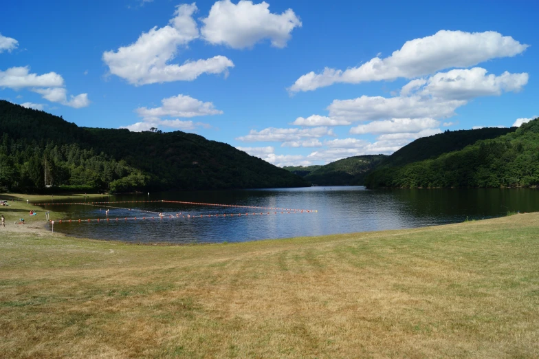 a big lake surrounded by hills with clouds