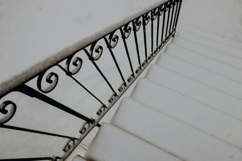 a snowy staircase with wrought iron railing