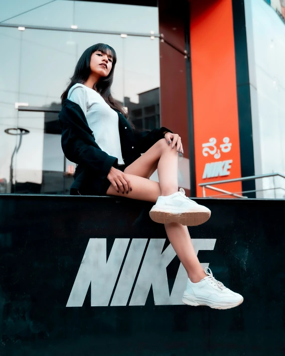 a girl sitting on a bench in front of a nike store