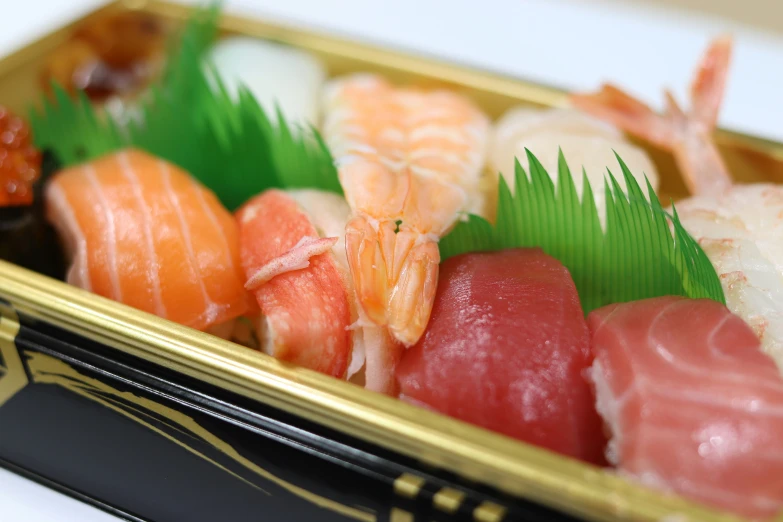 a gold container with assorted sushi in it