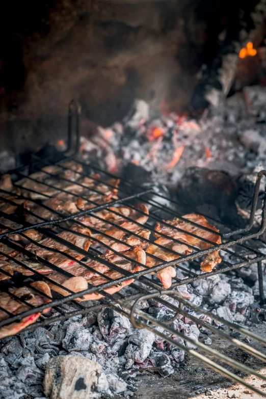 barbecue grill with several meats being cooked over charcoal