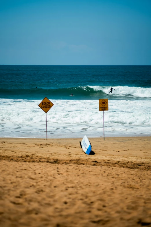 a surf board lying on the beach, with a surfboard sticking out of it