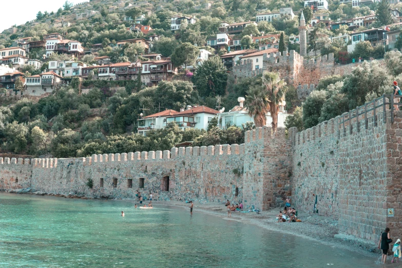 a wall by the water that has people in it