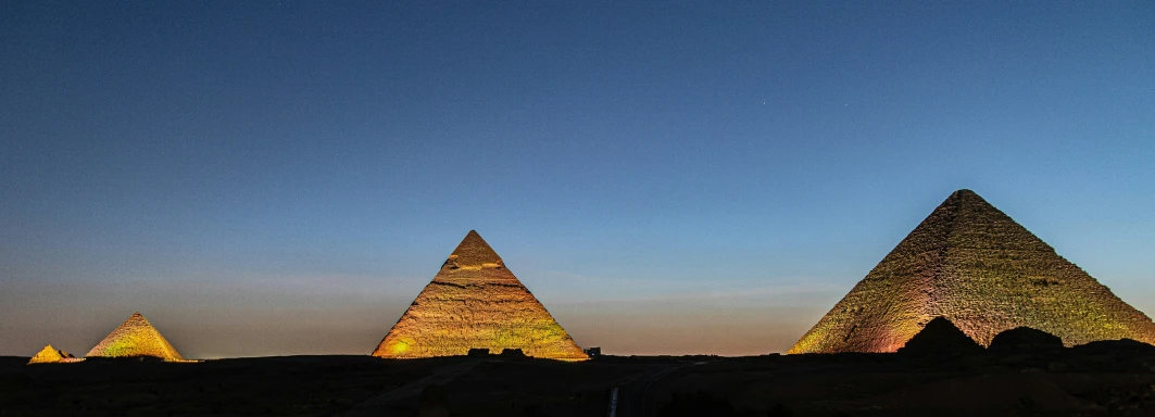 four pyramids are illuminated against the sky at night