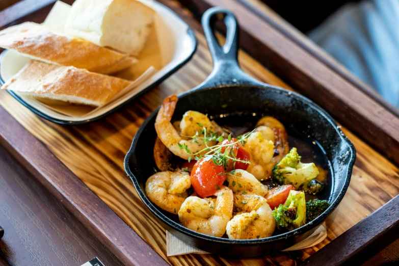 a pan of shrimp, tomatoes and bread is sitting on a table