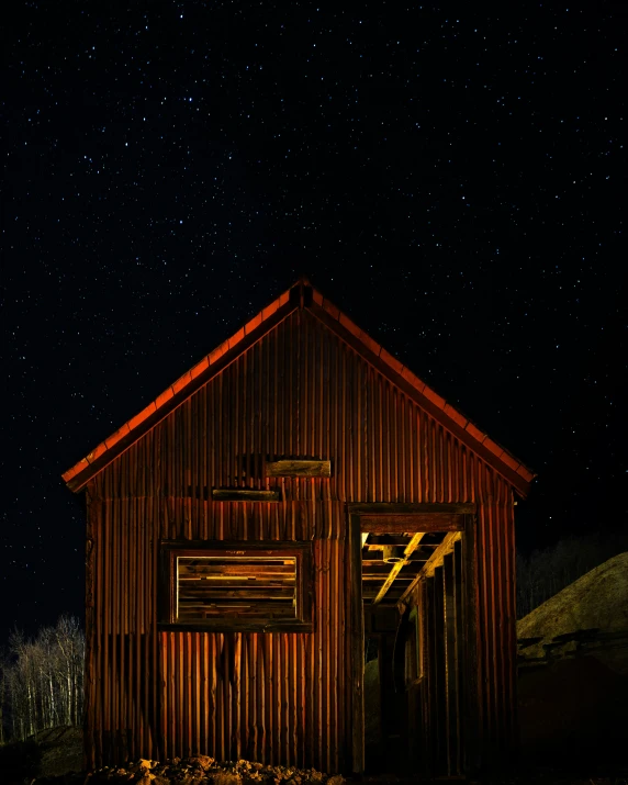 an old barn lit up at night with stars