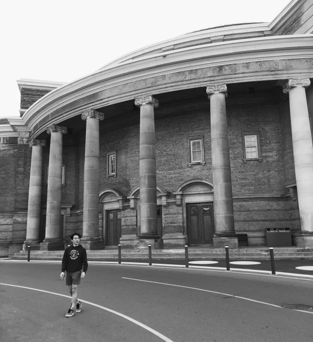 black and white pograph of a man skateboarding in front of a building