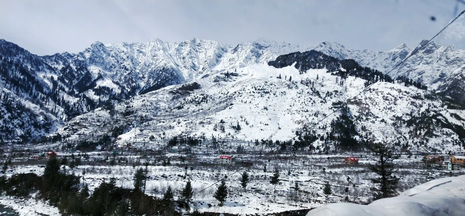 a mountain range with trees in the foreground and snow covered mountains