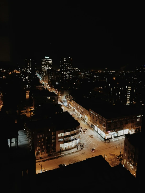 a dark night with street lights, a city and buildings in the background