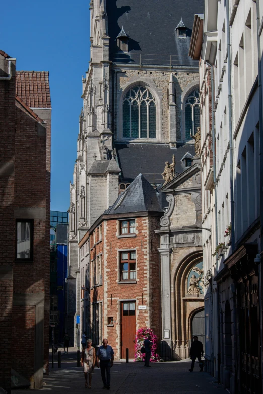 some people walk down a cobblestone street in front of a church