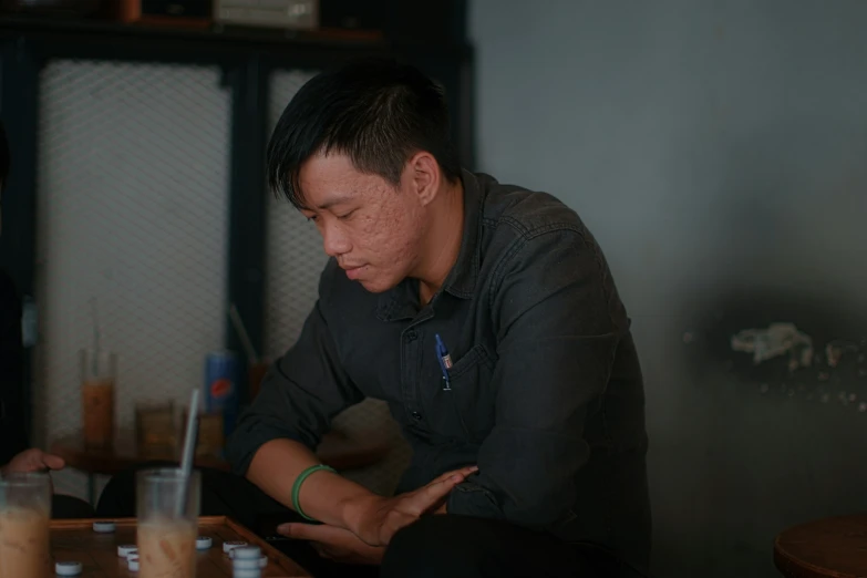 two men sitting at a table with a beer and a cigarette