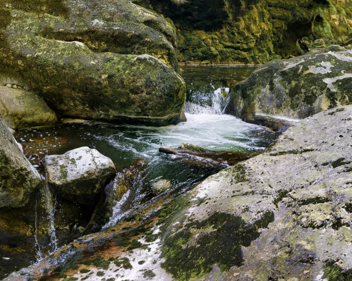 two people climb on the side of rocks in the water