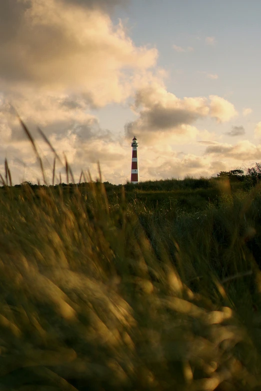 a light house sitting above the grass at dusk