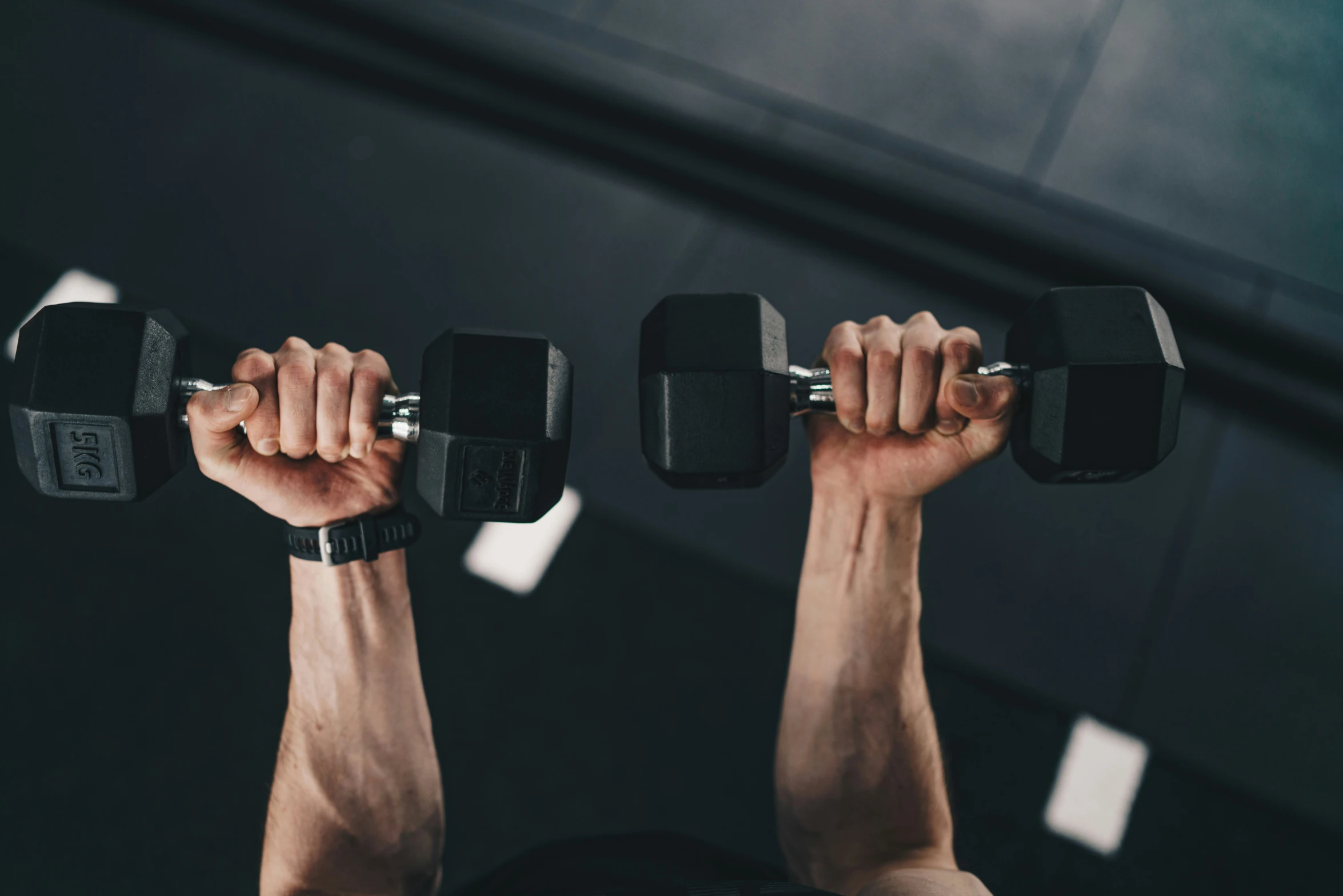 the legs of a man doing squats with two dumb presses