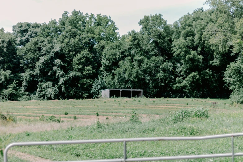 an empty field has a fence and a large building in it