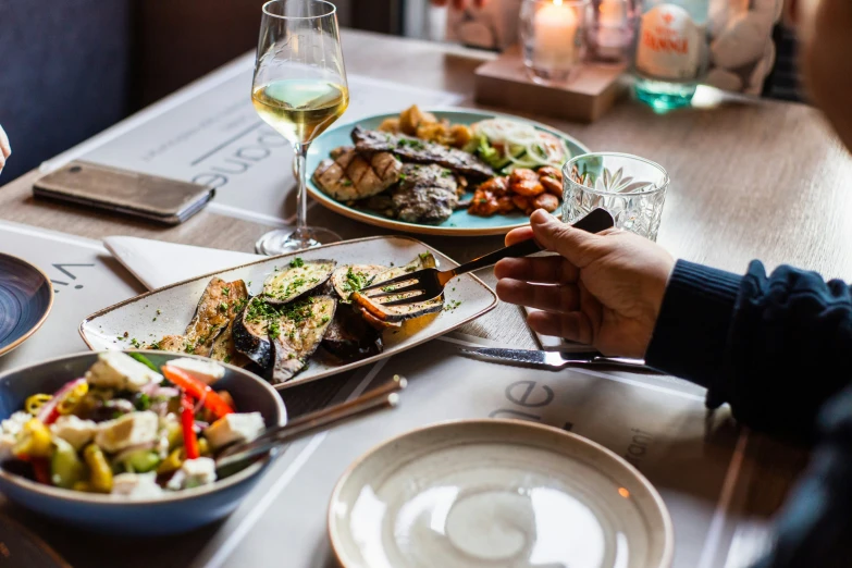 a person holding a plate of food while sitting at a table