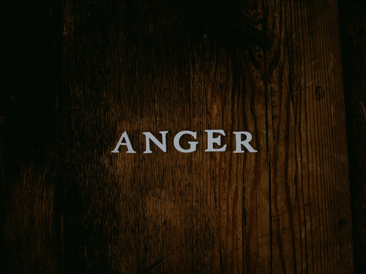 an old wood door has the word anger written on it