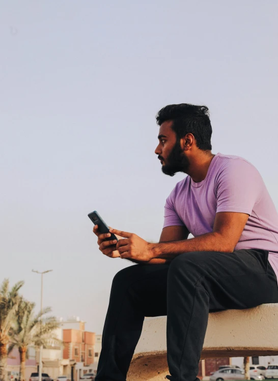 a man is sitting on a park bench and looking at his cellphone