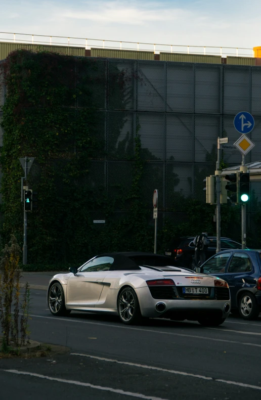 a white car parked next to another car near some traffic lights